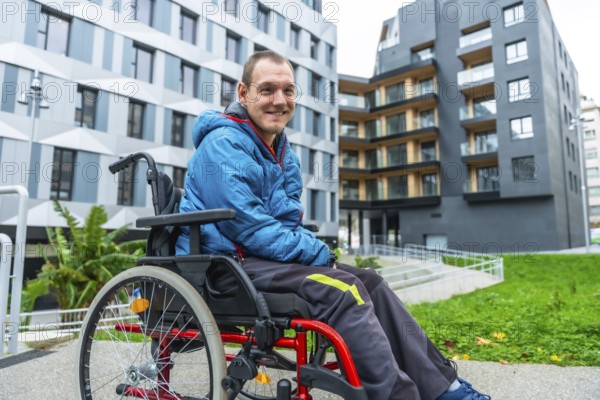 Smiling man with a disability navigating a modern urban environment in his wheelchair, highlighting