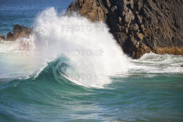 Waves crash against rocks at the mainland's easternmost point, creating rainbows in the ocean spray