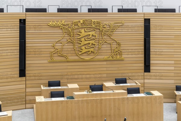 Plenary hall deserted with the seats of deputies and the government bank. Behind it is the coat of