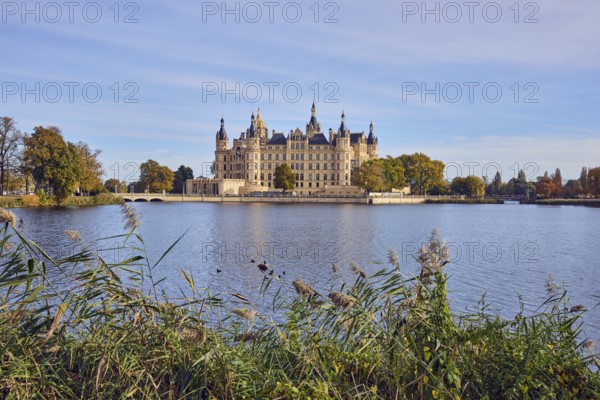 Castle, lake Burgsee, reed (Phragmites australis), trees, bushes, car bridge and pedestrian bridge,
