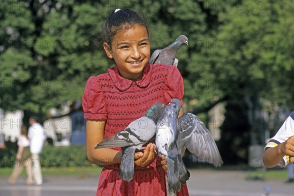 A girl holding two doves and feeding them, Placa de Catalunya, Barcelona, Spain, June 1999,