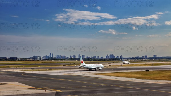 Airport with plane taking off in front of a skyline under a partly cloudy blue sky, view from an