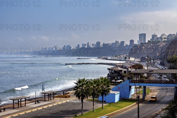 Coastal road with palm trees and views of the seaside city surrounded by cliffs and skyscraper