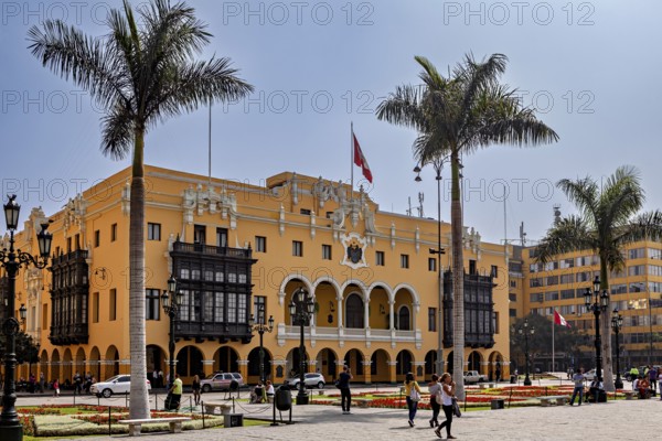 Colonial building with arches and national flag, surrounded by palm trees, in a sunny square, The
