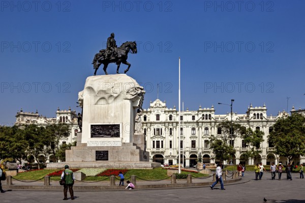 Equestrian statue in front of a flower-decorated base in a square with white buildings, Downtown