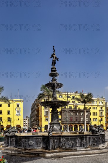 Historic fountain in a square with yellow buildings and palm trees under a blue sky, The historic