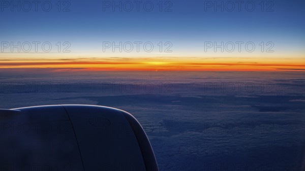 Sunset with dark sky and aircraft engine, On a plane above the clouds