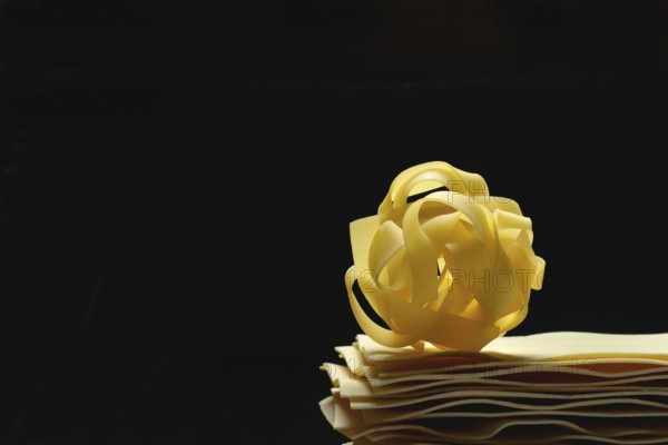Uncooked lasagna leaves and fettuccine, noodle nest