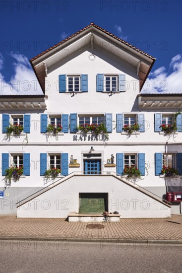 Town Hall, façade with windows and shutters, flower boxes, double stairway, blue sky, cumulus