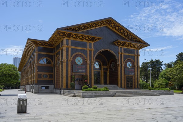 In sunlight, an artfully designed wooden building with well-kept surroundings and clear skies,