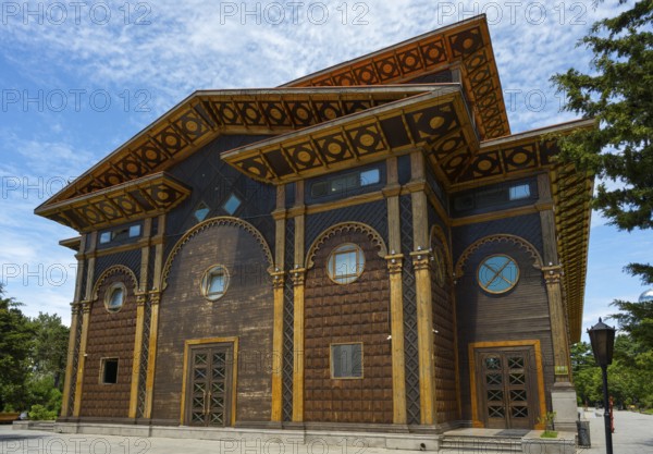 A distinctive wooden building with artistic decorations against a tranquil backdrop, Summer