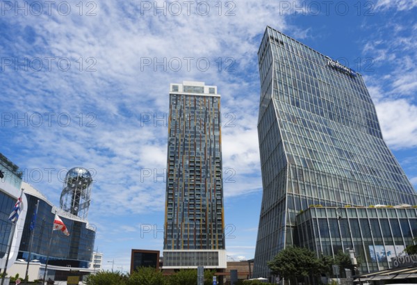 Two modern high-rise buildings with glass facades under cloudy sky, Radison Blue on the right and