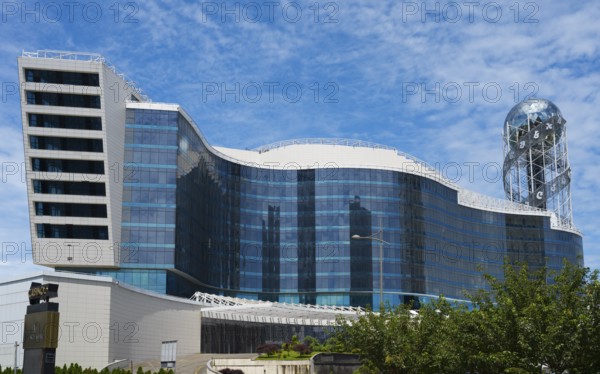 Modern building with wave-like design and glass façade under blue sky, business loft, right