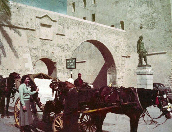 Horse and carriage taxi in city street next to Cabs Vetture sign and Roman statue of Emperor