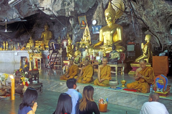 Buddha statue, monks and believers praying, Wat Tam Sua monastery near Krabi, Thailand, December