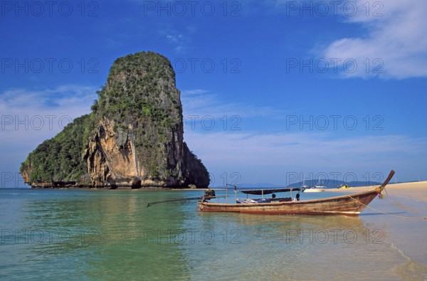 Rocks in the sea and longtail boat on Pranang Cave beach, two years in front of the tsunami, Krabi,