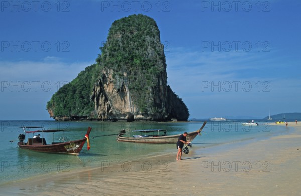 Rocks in the sea, people and longtail boats on Pranang Cave beach, two years in front of the