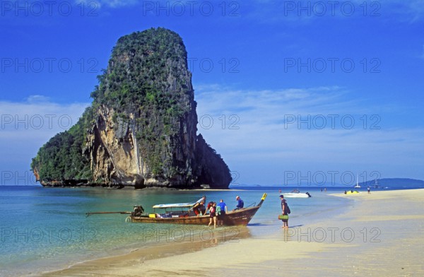 Rocks in the sea, people and longtail boat on Pranang Cave beach, two years in front of the