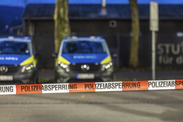 Flutter tape with the inscription police barrier. Behind them, police vehicles. Stuttgart,