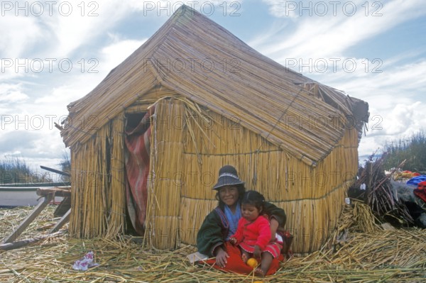 Children sitting in front of a reed hut on a floating Uro island in Lake Titcaca, Peru, South