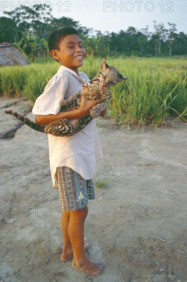 A boy whose father runs a small private zoo near Iquitos in the Amazon shows an ocelot (Leopardus