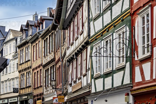 A series of half-timbered houses in various colors that form a lively street scene, The historic