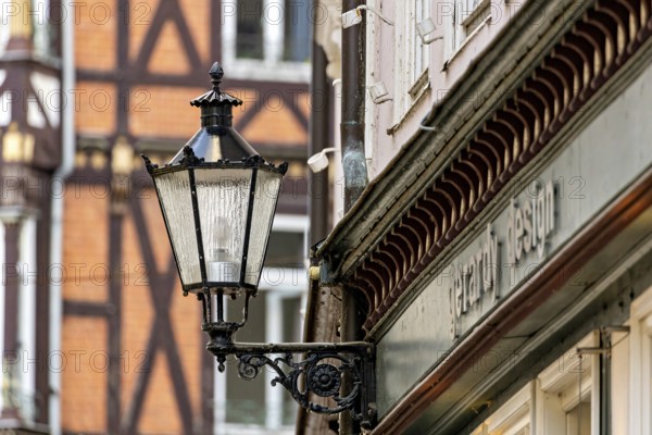 Nostalgic lantern next to a building in front of half-timbered buildings and windows in urban