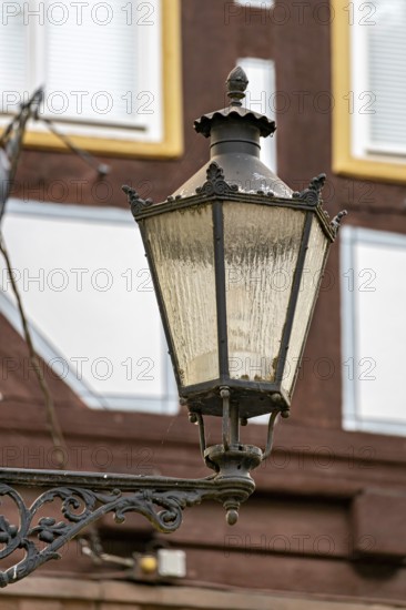 Nostalgic lantern in front of a half-timbered house with windows in a traditional cityscape, The