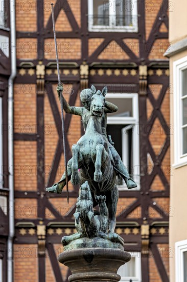 Bronze equestrian statue in front of half-timbered houses in urban surroundings, medieval flair,