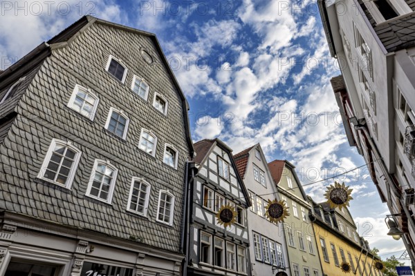 View of half-timbered houses under a vivid blue sky with decorative sun ornaments, The historic old