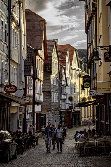 A lively street scene at sunset with people sitting at cafés in the old town, The historic old town