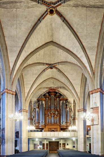 Impressive church interior with Gothic arches and imposing organ, atmospherically illuminated,
