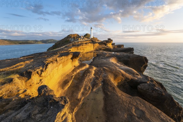 Castlepoint lighthouse on a rock, sea, sunrise. Castlepoint, Wairarapa Coast, Wellington Region,