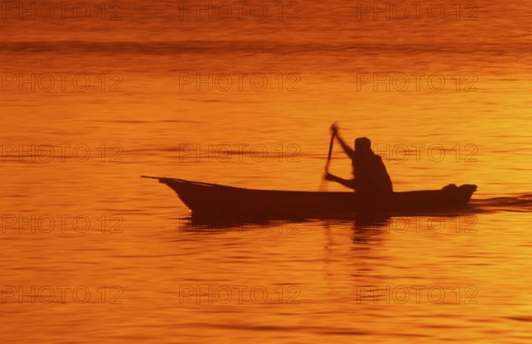 Silhouette of a fisherman in his boat at sunrise near Mikadi Beach, Dar es-Salaam, Tanzania,