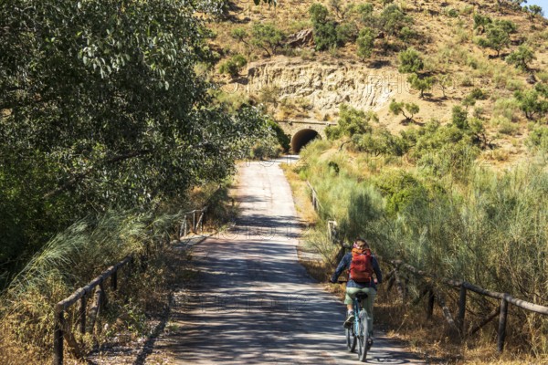 Woman riding a bycicle, cycle path Via Verde de la Sierra, path leads through a tunnel, Puerto