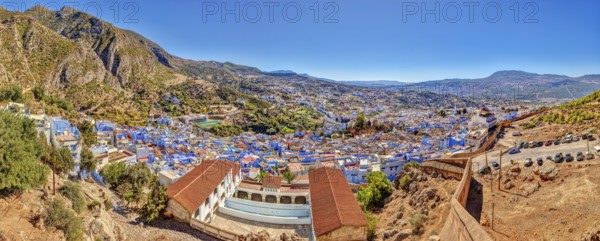 Panoramic picture of a city with distinctive blue buildings and mountainous surroundings, Morocco,