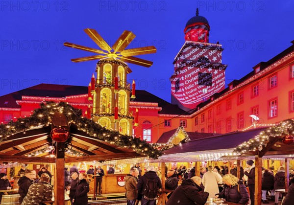 The Christmas market with the mulled wine pyramid and the illuminated town hall in the evening,