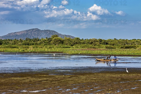 A small boat on a lake in a peaceful landscape with mountains in the background and a sky full of