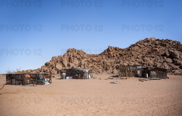 Simple poor huts made of corrugated iron and wood, desert landscape, barren landscape with hills of