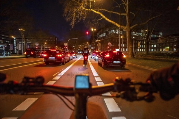 Cycling in the city, in the dark, in the evening, cycling on a bike lane, marked in red,