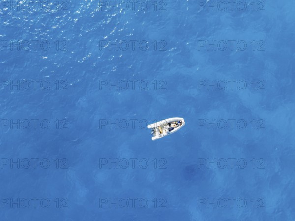 Young woman and young man lying in a motor boat on a blue sea, top-down, aerial view, Golfo di