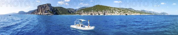 Motor boat off picturesque rocky coast, cliffs and Cala Luna beach, aerial view, Golfo di Orosei,