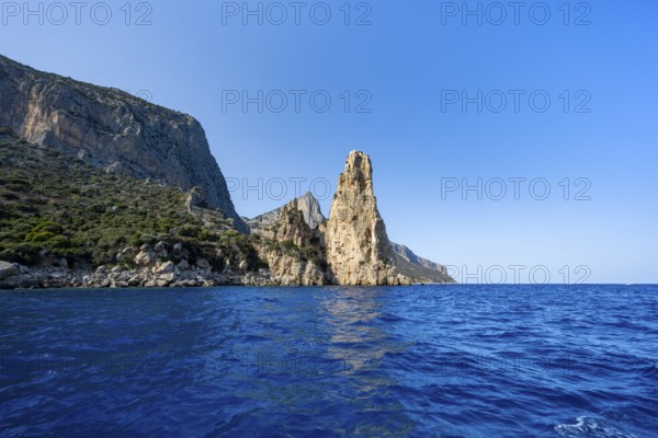 Picturesque rocky coast, cliffs with Pedra Longa pinnacle in the evening light, blue sea, Golfo di