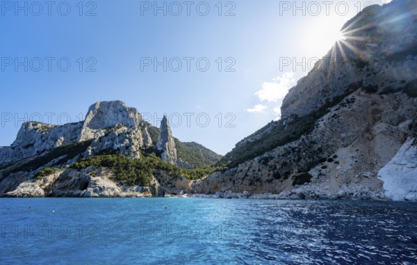 Picturesque rocky coast, cliffs with L'Aguglia pinnacle, blue sea and Cala Goloritzé beach, sun
