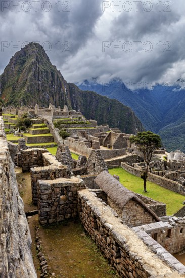 View of the ruined city of Machu Picchu with surrounding Andes and cloudy sky, The ruins of the