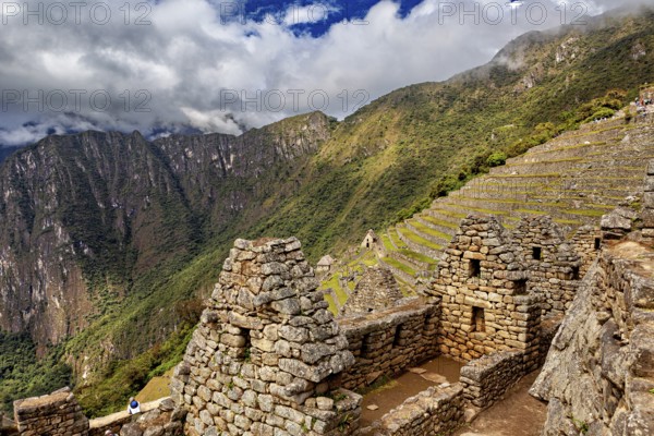 Old stone buildings with terraces in a mountainous landscape under clouds, The ruins of the Inca