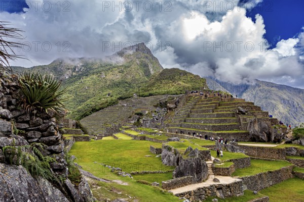 Inca terrace landscape under dramatic sky with clouds and mountain peaks near Machu Picchu, The