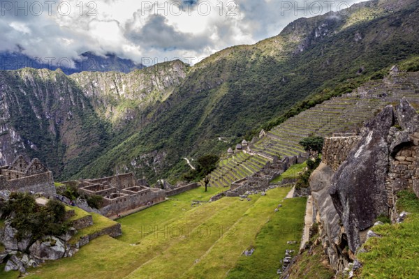 Descending terraces of ruins against mountain backdrop and cloudy sky, The ruins of the Inca city