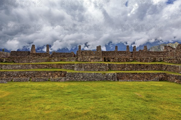 Plain with ancient stone ruins and grassy surfaces under a cloudy sky, The ruins of the Inca city