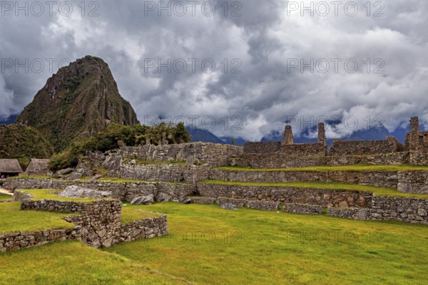 Ancient ruins against a dramatic sky with dark clouds and green areas, The ruins of the Inca city